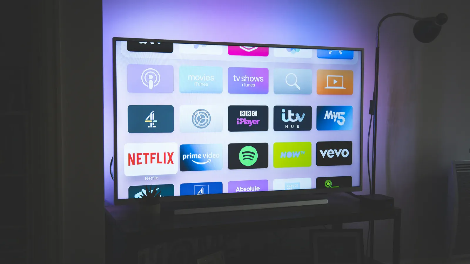 Et moderne fladskærms-tv på en væg i en stue med dæmpet belysning.